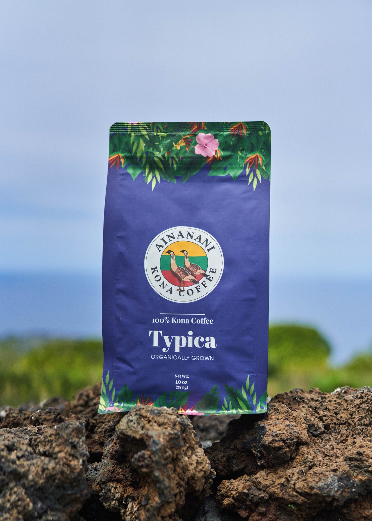 Ainanani 100% Kona Typica coffee bag on lava rock above the ocean in Kona, Hawaii